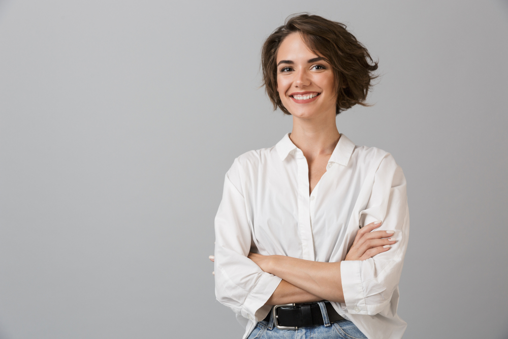 A smiling woman with short brown hair and crossed arms, exuding confidence from Renewal Family Dental.