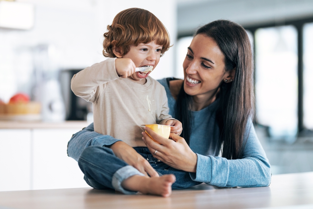 A smiling mother feeding her happy child, representing the nurturing care provided by Renewal Family Dental.