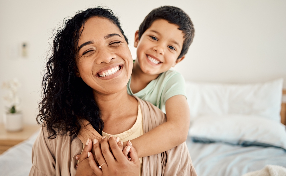 A joyful mother and child embracing and smiling brightly, representing the happy families served by Renewal Family Dental.