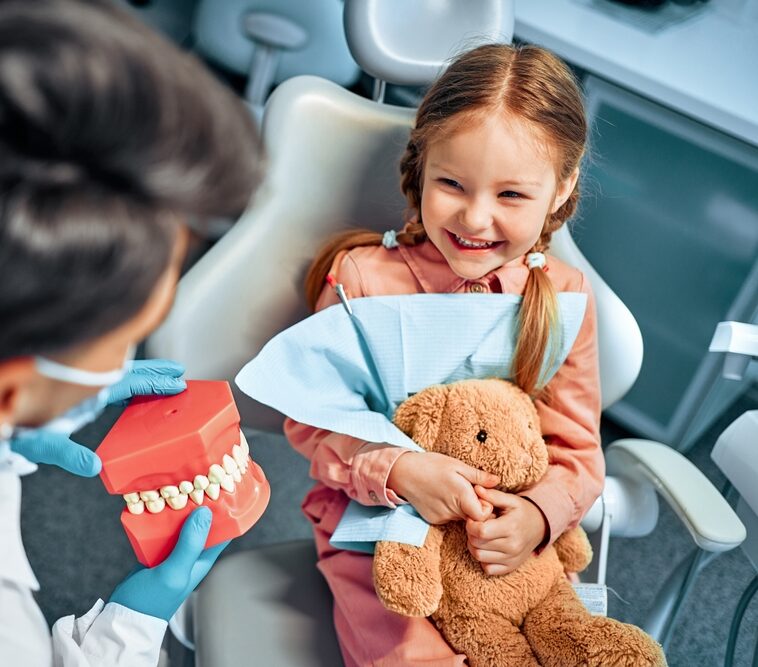 A smiling child with a teddy bear at a dental visit, promoting Preventative Dentistry in Dearborn at Renewal Family Dental