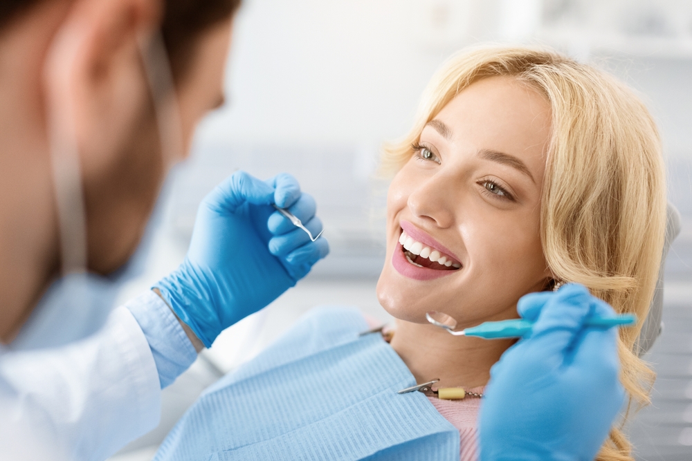 A smiling new patient in Dearborn happily receiving dental care from a dentist at Renewal Family Dental.